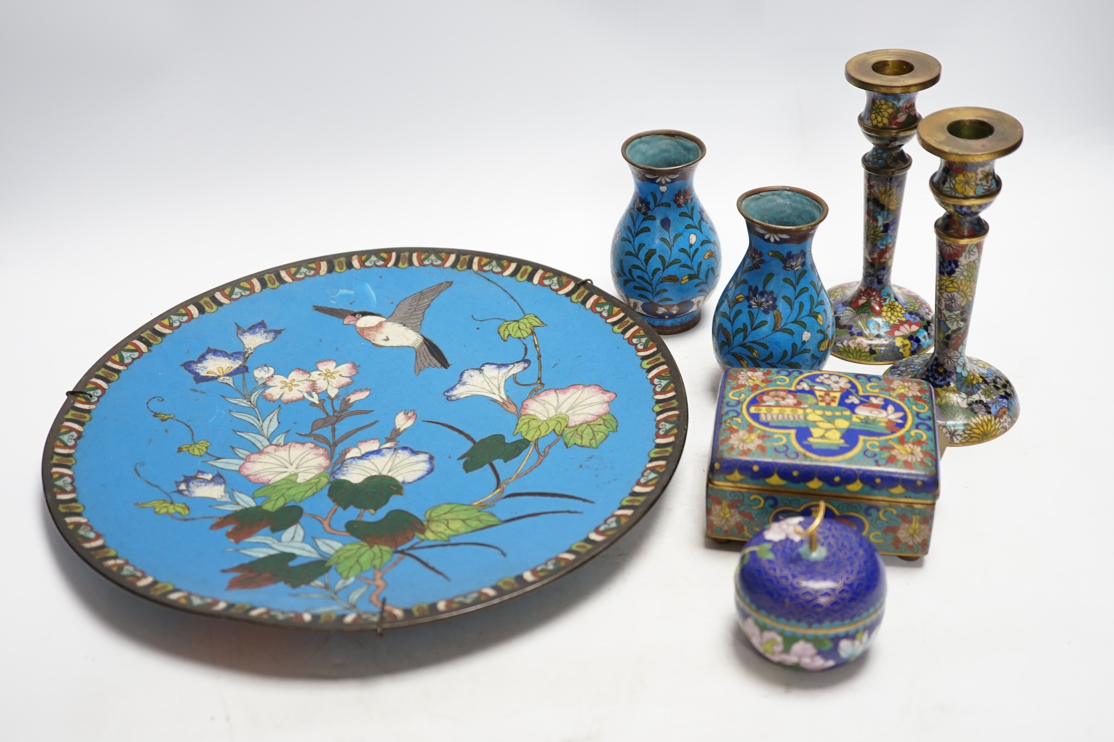 Seven Chinese or Japanese cloisonné enamel items including a pair of candlesticks, 15cm high, a charger, two boxes and a pair of vases